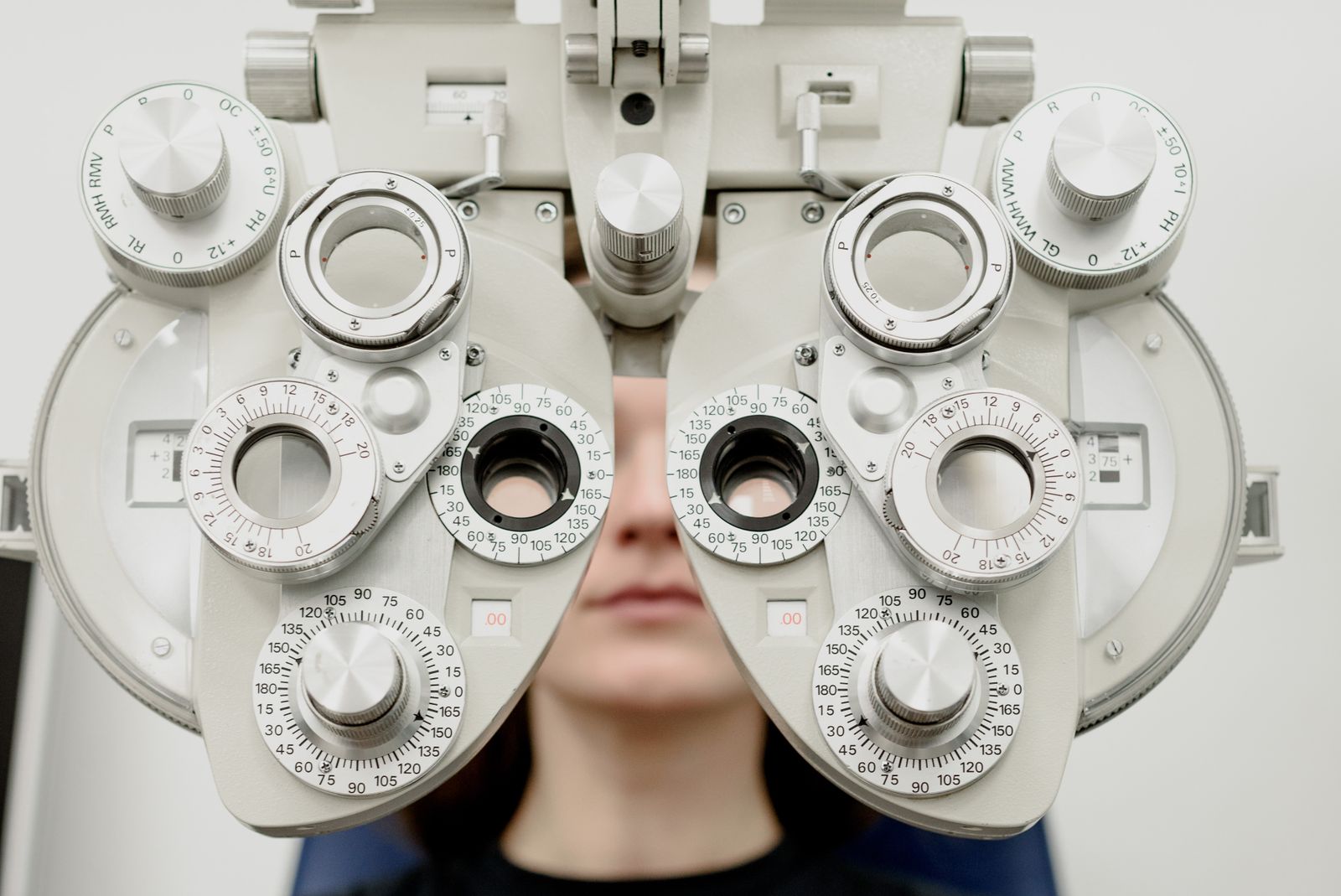 Patient undergoing a refraction test through a phoropter during a comprehensive eye exam at Visions Optique & Eyecare, North Scottsdale
